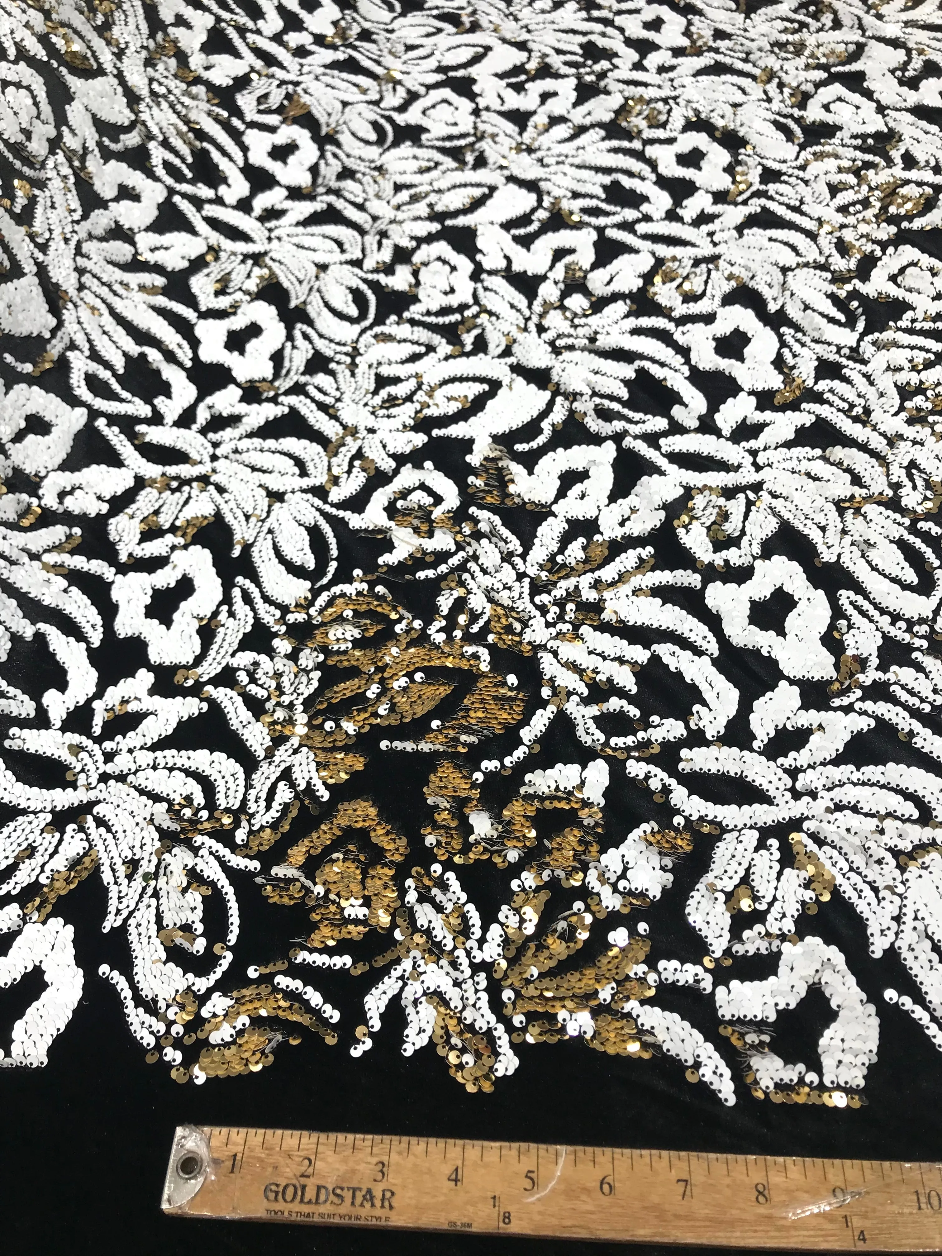 White/gold sequins flip two tone floral design on a black stretch velvet, Sold by the yard.